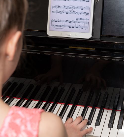 Jeune fille jouant du piano devant une tablette